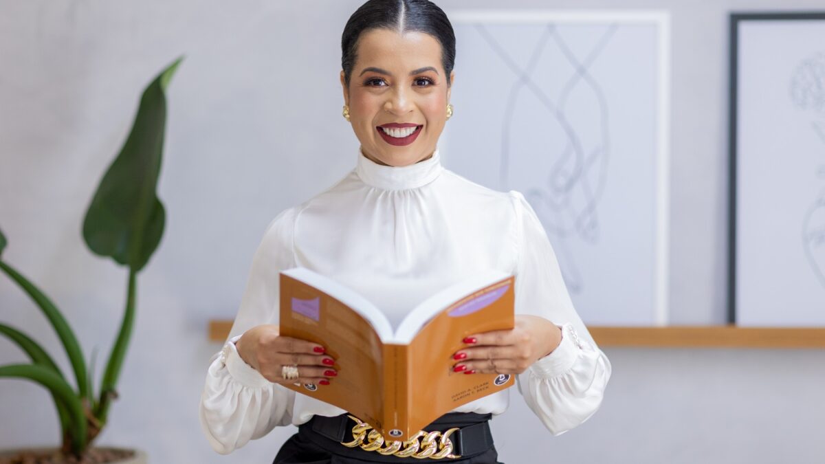 Daniele Barros, psicóloga, segurando um livro de Terapia Cognitivo-Comportamental