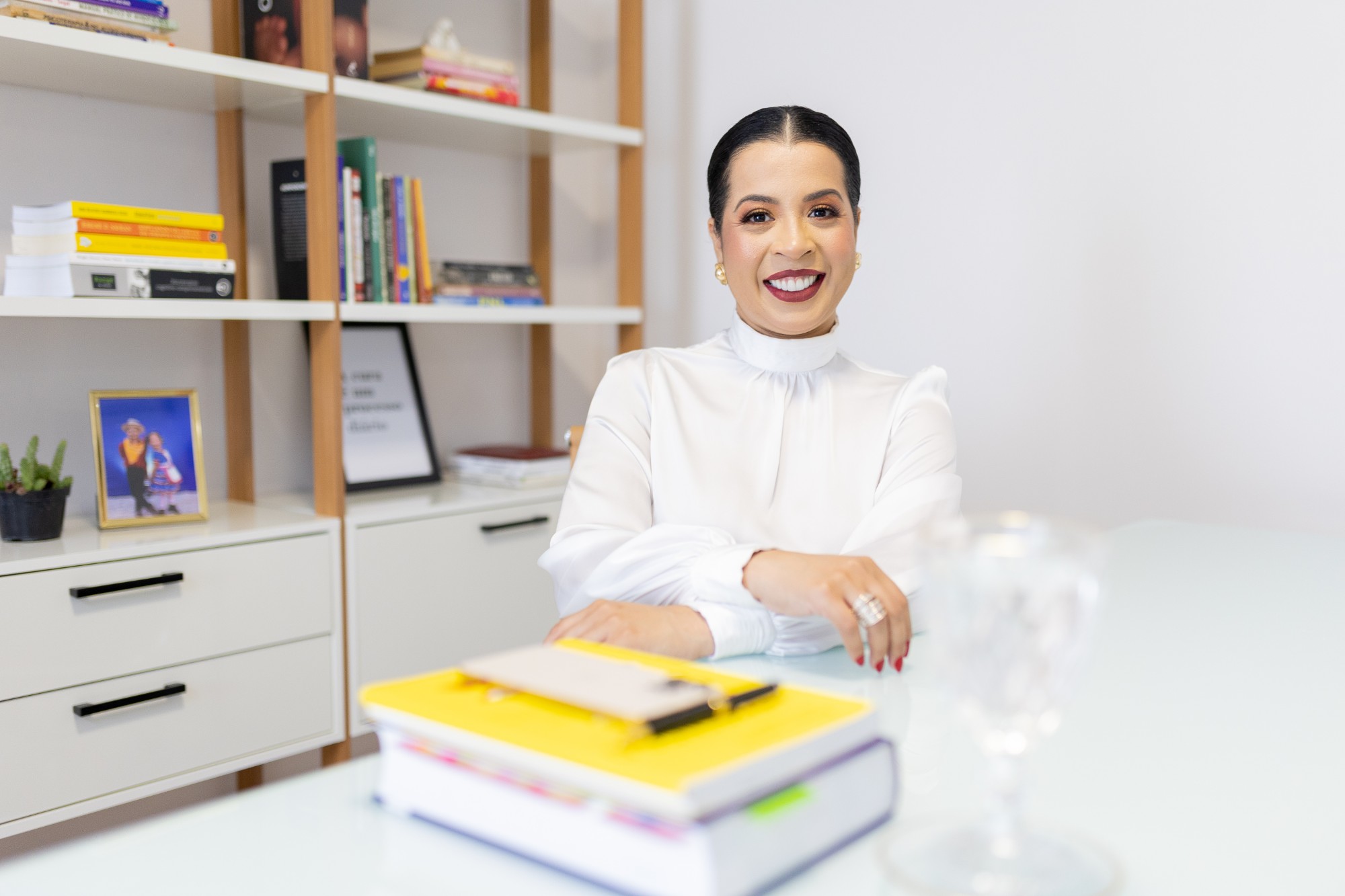 Daniele Barros, psicóloga em Goiânia, sorrindo em seu consultório