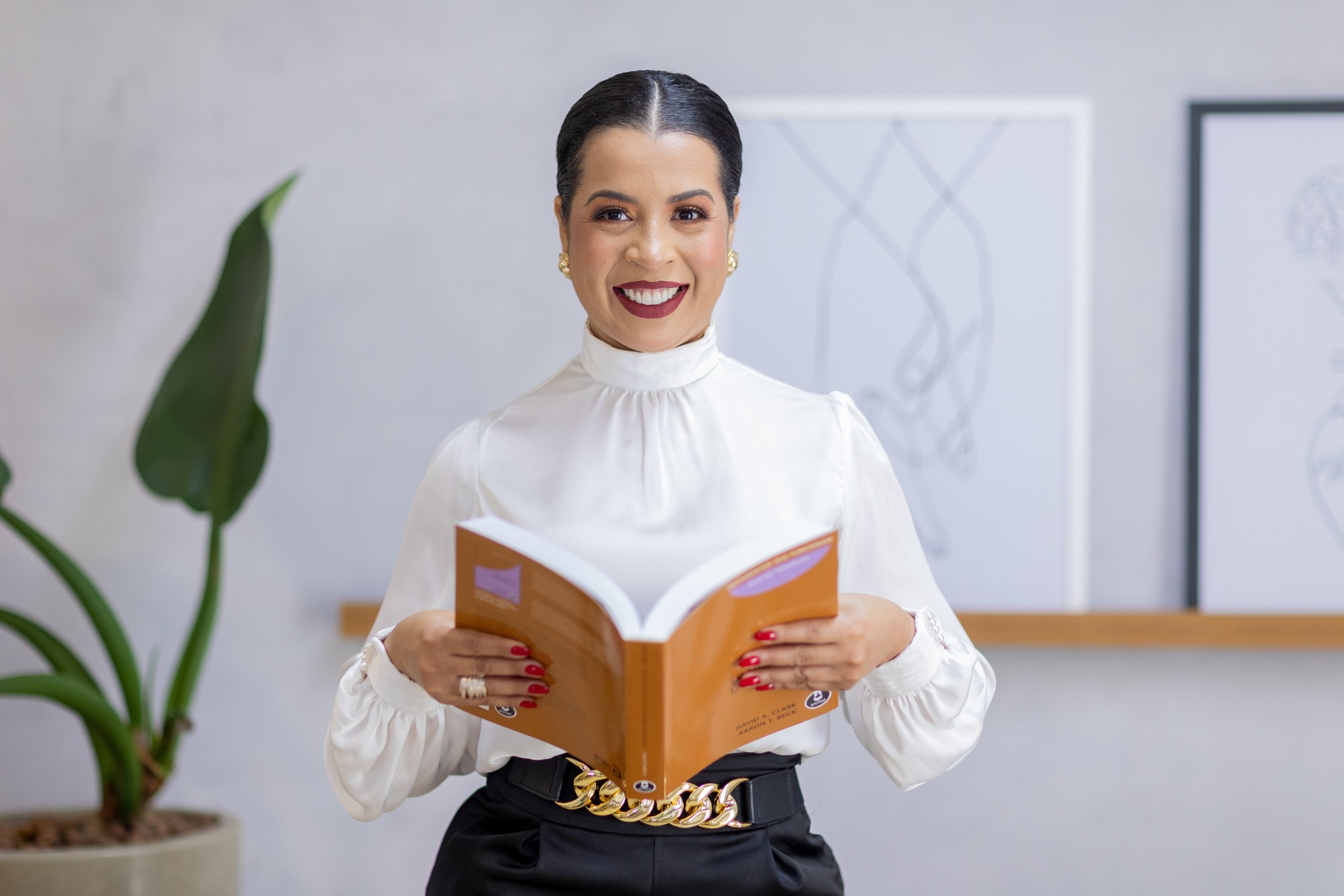 Daniele Barros, psicóloga em Goiânia, segurando livro sobre Terapia Cognitivo-Comportamental