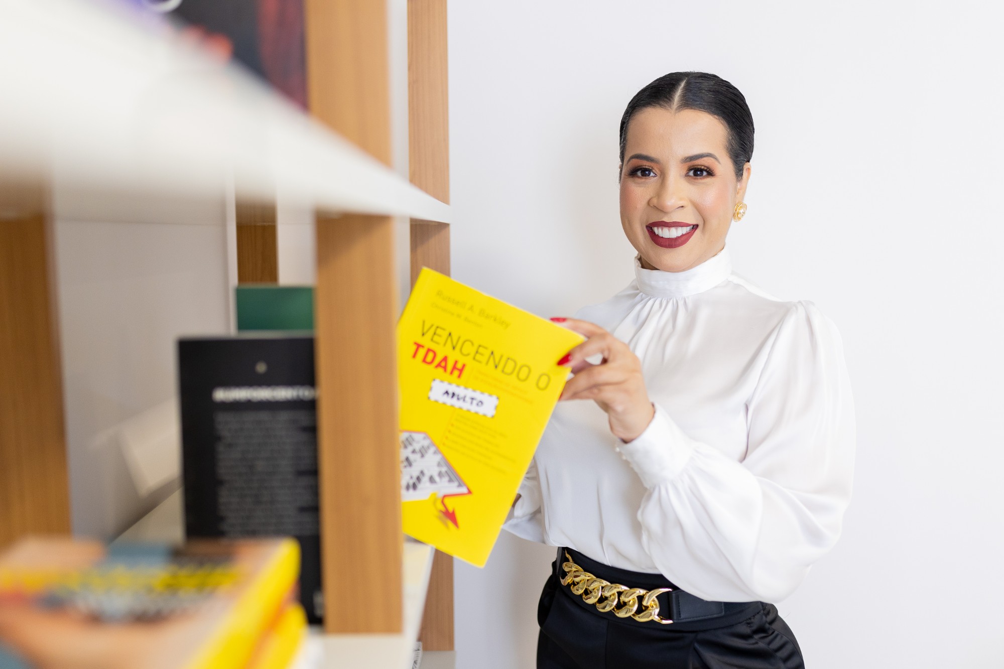 Daniele Barros, psicóloga em Goiânia, segurando livro sobre TDAH em adultos
